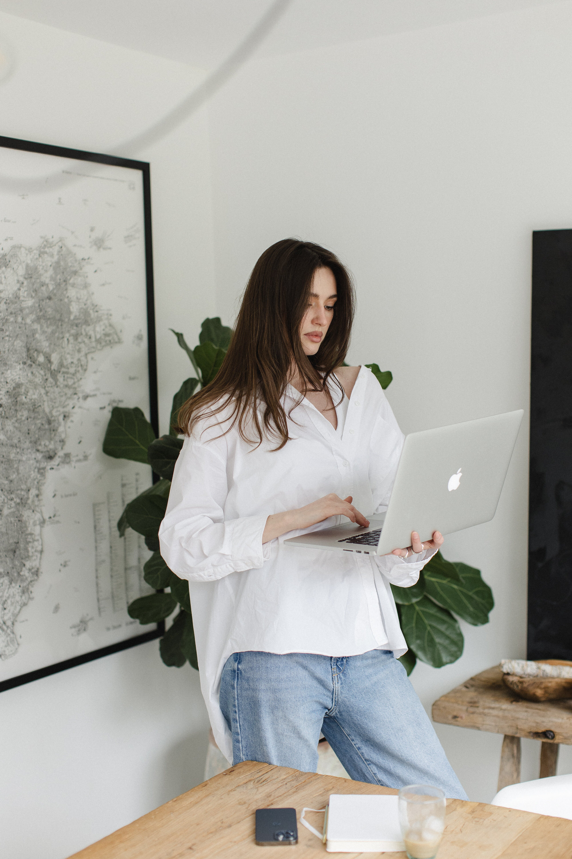 Women wearing white shirt and typing on laptop whilst standing up